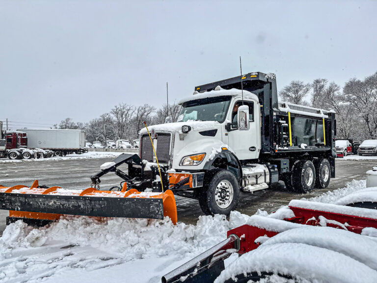 Snow removal dump truck showing plow and spreader in parking lot, constructed by Master Tech in Kansas